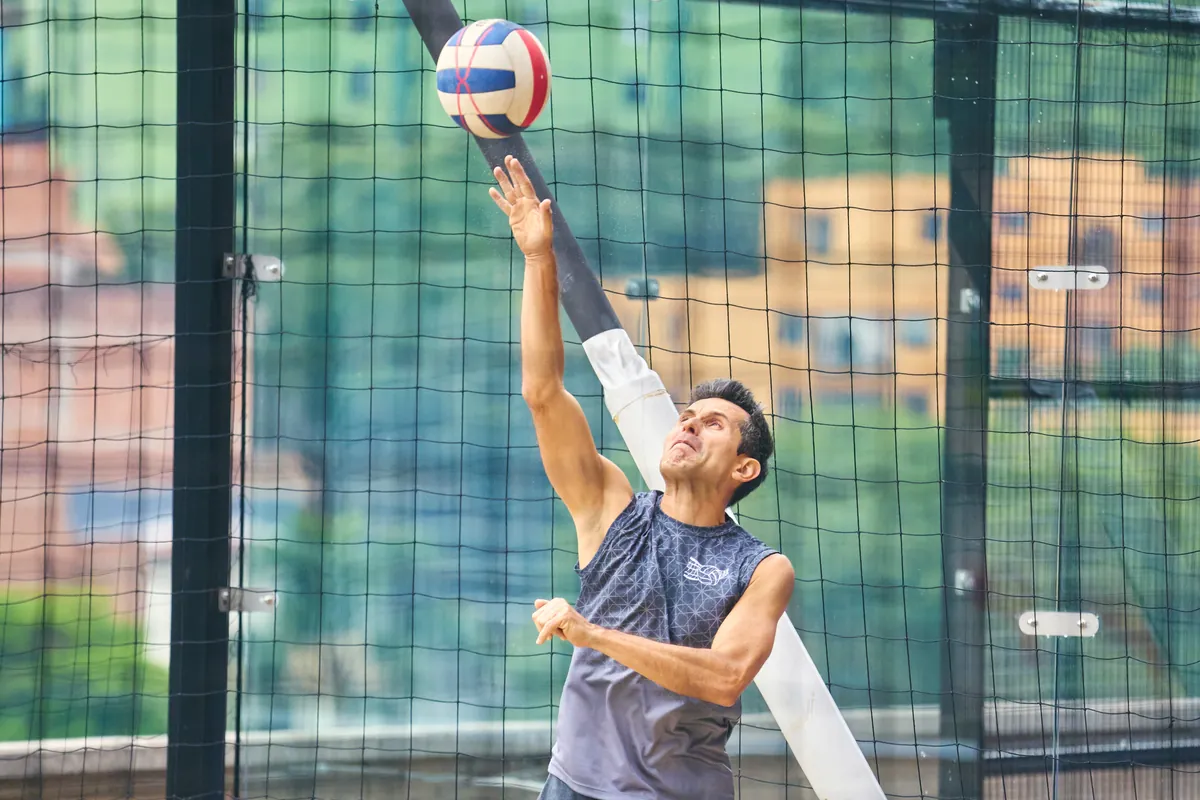 Jugador de vóley playa realizando un saque en una cancha de La Jaula
